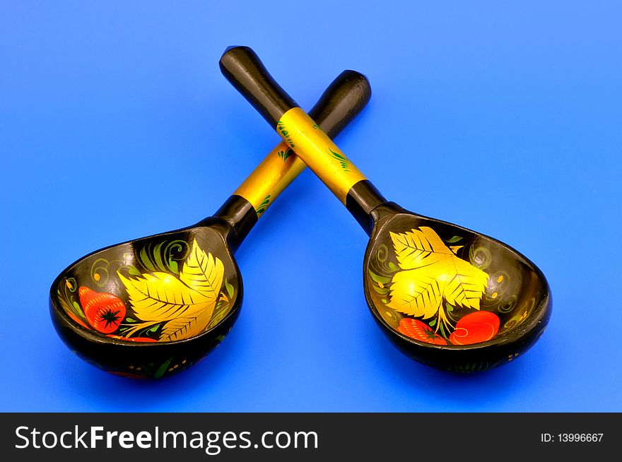 Two decorative, painted spoons photographically on a blue background