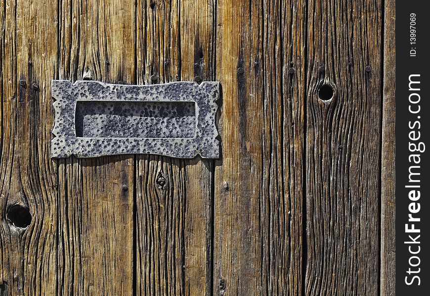 Metal mail slot mounted on rough wooden planked door. Metal mail slot mounted on rough wooden planked door