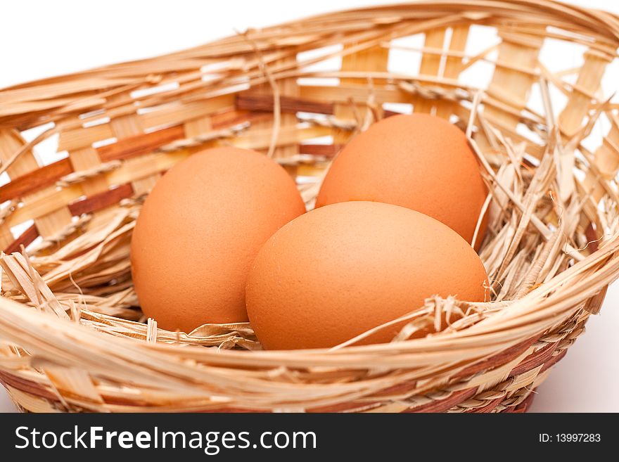 Brown Eggs in a basket with straw on a white background