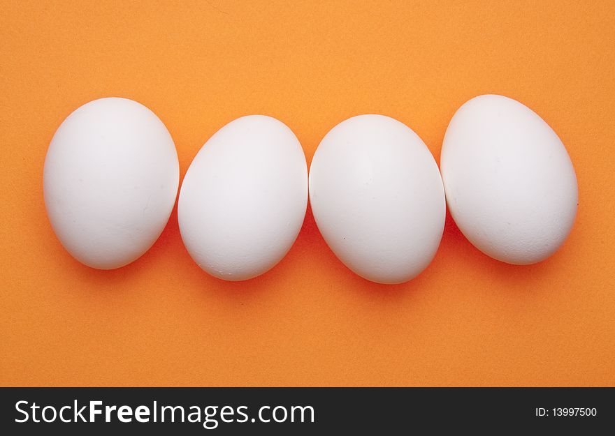 Line of Eggs on a Vibrant Orange Background.