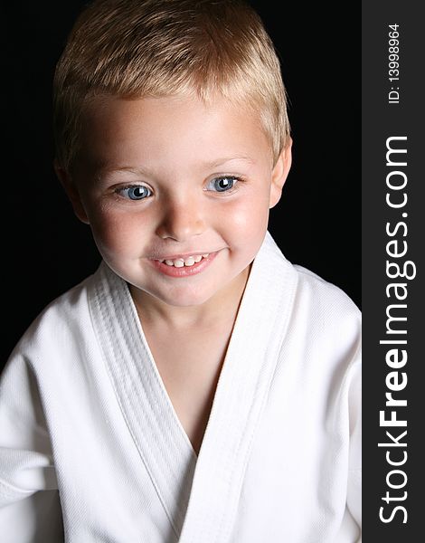 Young boy wearing his karate uniform on a black background. Young boy wearing his karate uniform on a black background