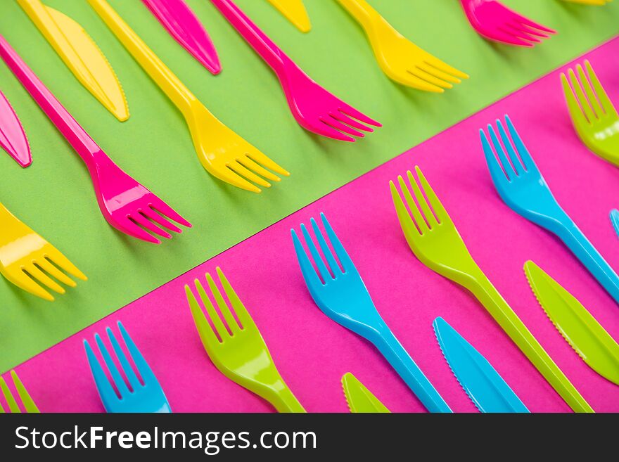 Composition of colorful plastic cutlery on a bright background top view. Composition of colorful plastic cutlery on a bright background top view