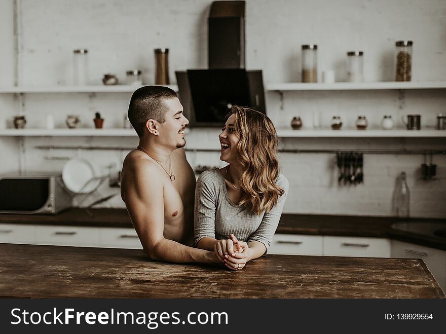 Authentic beautiful loving couple are kissing and hugging in the kitchen