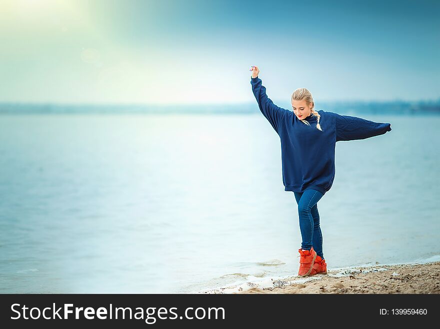 Girl dancing on the river beach in spring or autumn