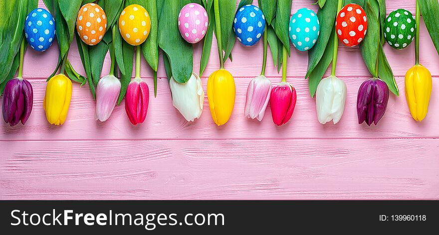 Easter eggs with colorful tulips on wooden background, easter holiday concept.