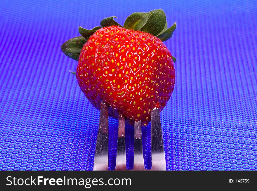 Photo of a Strawberry on a Fork With Blue Background