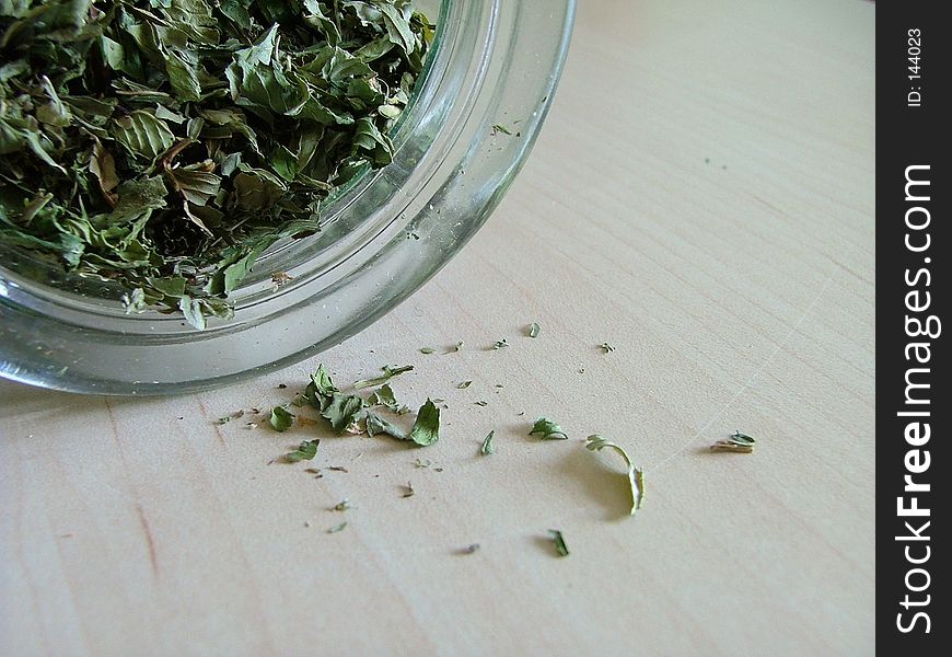 Green tea spilling out from a glass jar