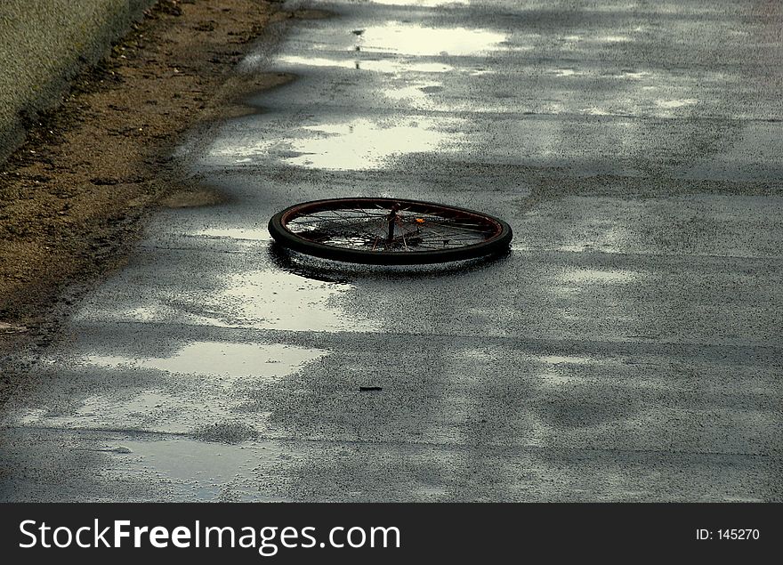 View of an old bike wheel on a roof in a rainy day. View of an old bike wheel on a roof in a rainy day