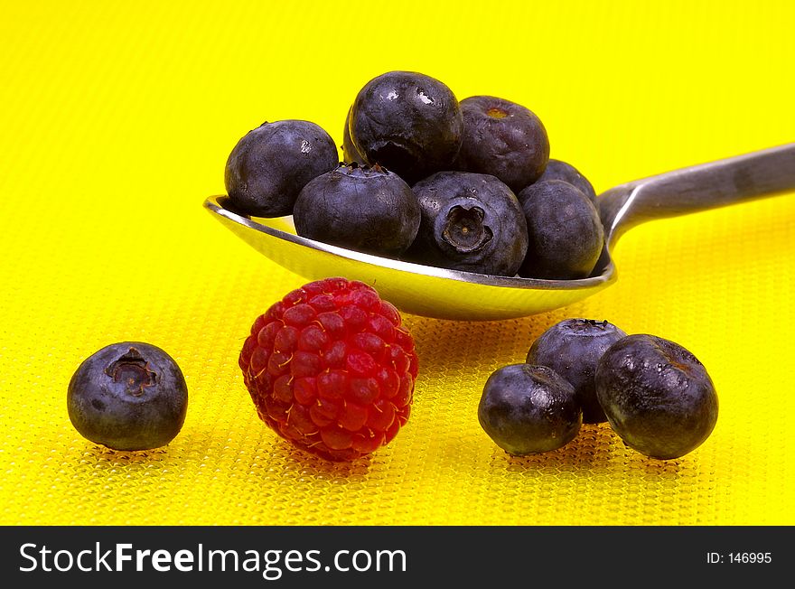 Spoon With Blueberries and a Raspberry. Spoon With Blueberries and a Raspberry