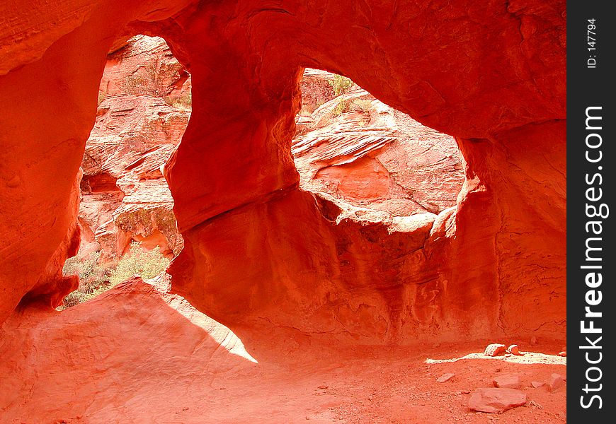 Red sandstone holes forming ghost eyes through wall.