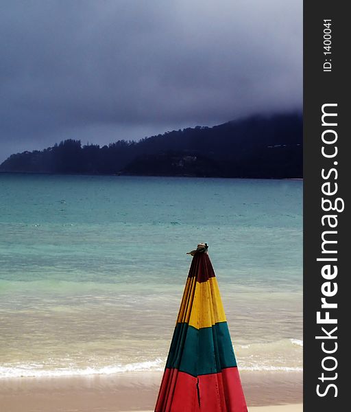 Seascape with umbrella in the foreground during monsoon season, Phuket, Thailand. Seascape with umbrella in the foreground during monsoon season, Phuket, Thailand