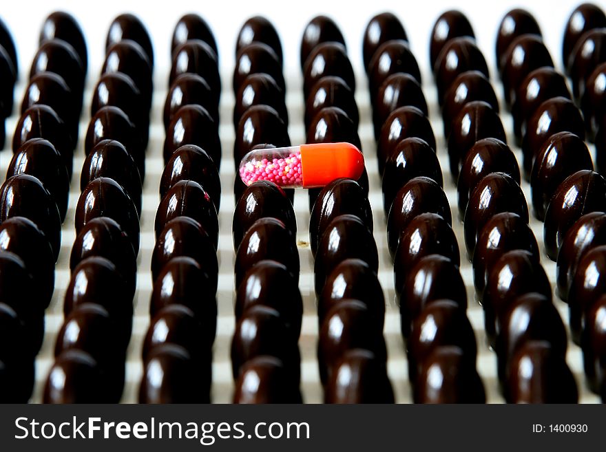 Red capsule upon many brown capsules.