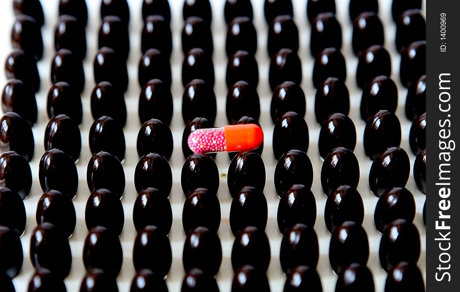 Red capsule upon many brown capsules.