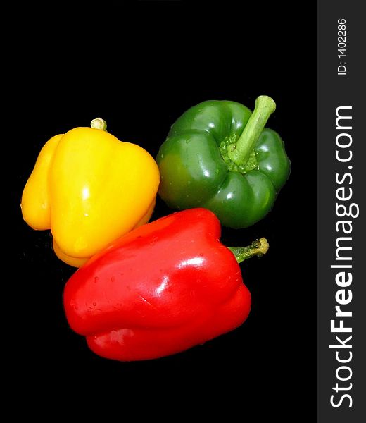 Red, yellow and green sweet peppers on black background