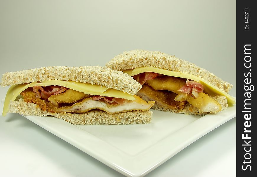 Wholemeal bread supersandwich of breaded xhixken breast, bacon and cheese