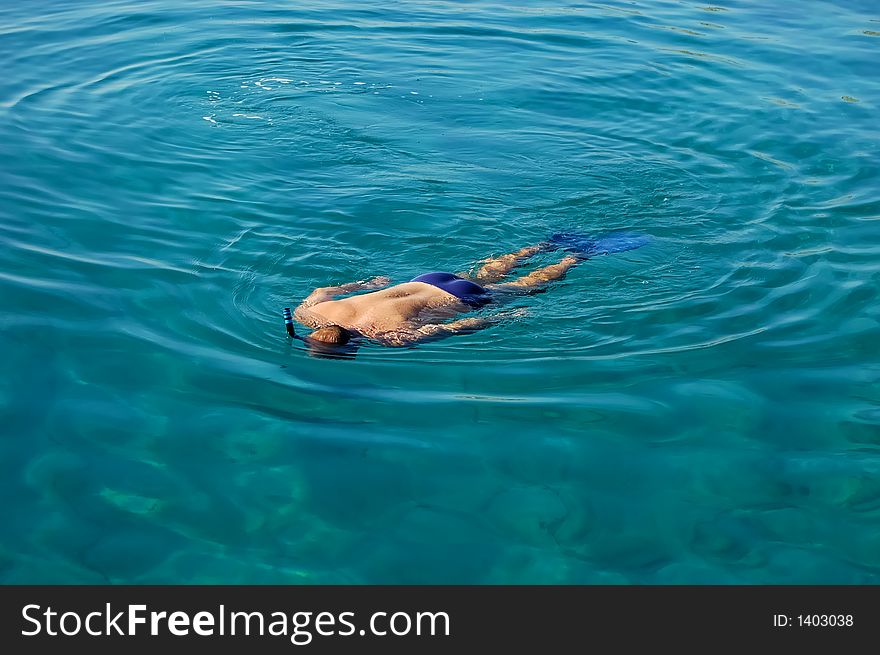 A guy snorkeling in clear blue sea