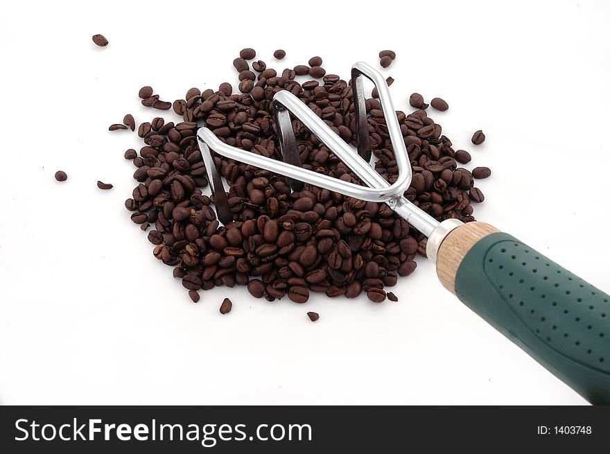 A gardening tool and coffee beans against a white background. A gardening tool and coffee beans against a white background.