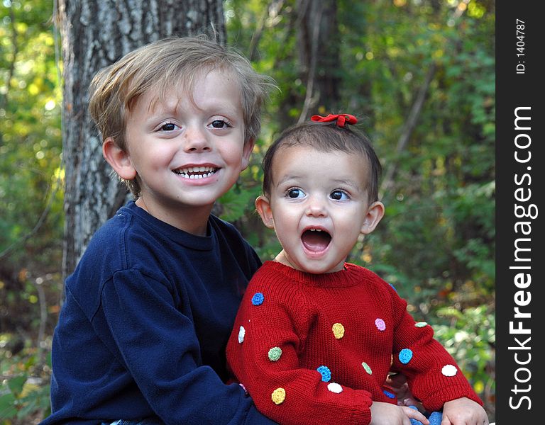 A little girl with her mouth wide-open and a young boy smiling in an outdoor setting. A little girl with her mouth wide-open and a young boy smiling in an outdoor setting.