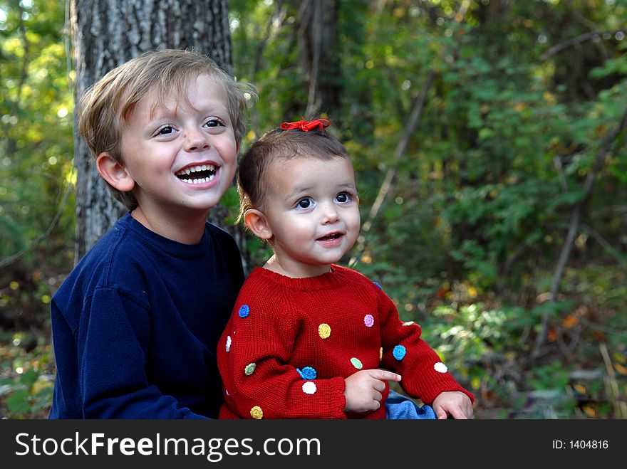 A little girl smiling and a young boy laughting in an outdoor setting. A little girl smiling and a young boy laughting in an outdoor setting.