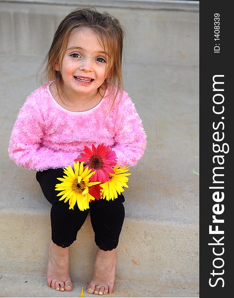 A little girl holding a bouquet of Gerber Daisies she picked from her mother's garden with a sweet smile on her face. A little girl holding a bouquet of Gerber Daisies she picked from her mother's garden with a sweet smile on her face.