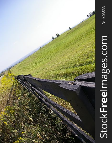 A brown wooden fence bordering a green field. A brown wooden fence bordering a green field