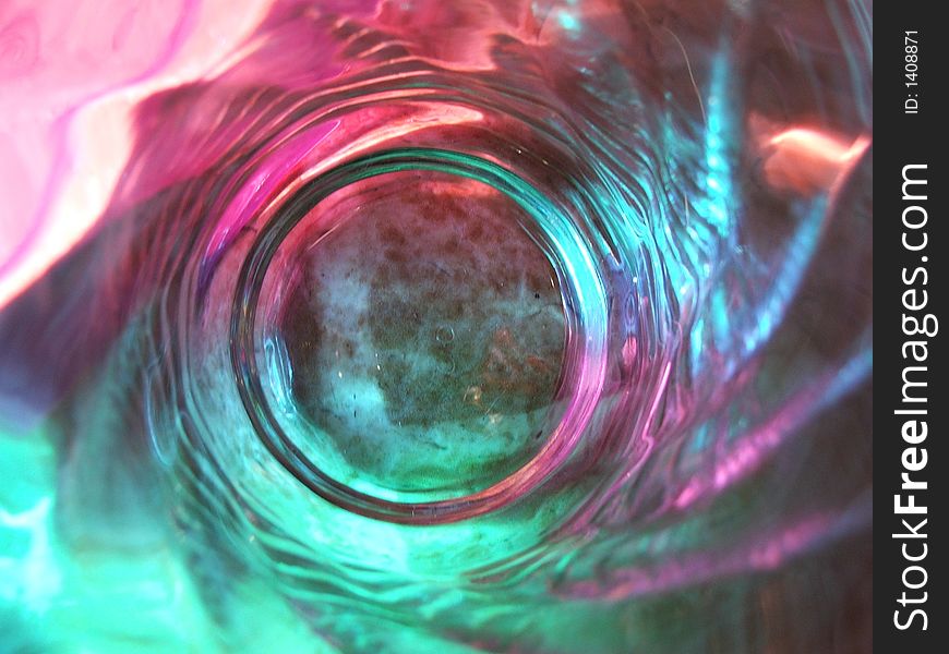 View down into a drinking glass while the light shone through colored filters.  The color & reflection was caught in the details of the glass in a swirl pattern. View down into a drinking glass while the light shone through colored filters.  The color & reflection was caught in the details of the glass in a swirl pattern.