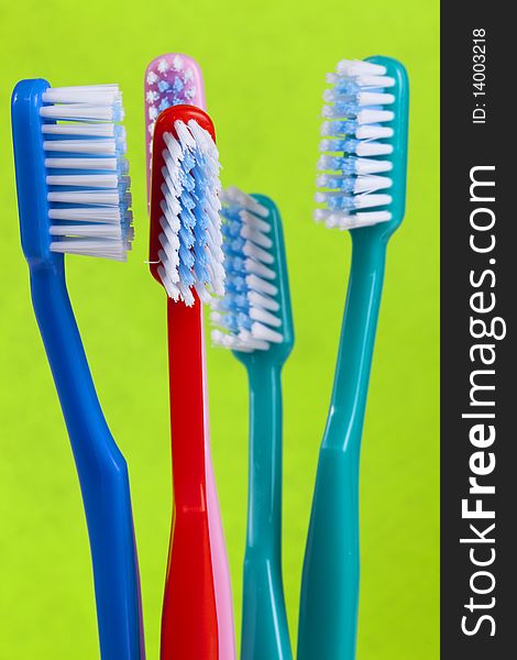 Colored toothbrushes on green background