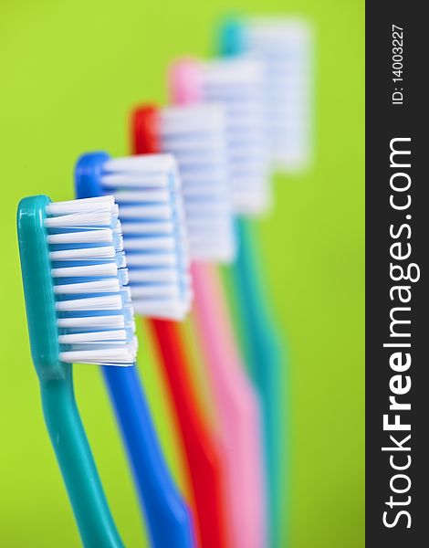 Colored toothbrushes on green background