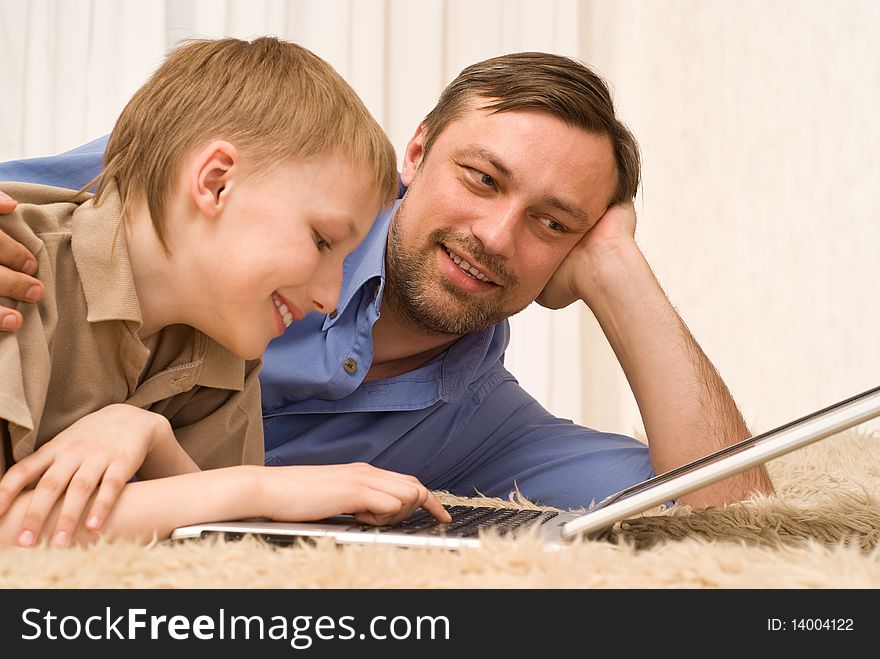 Father and son on the carpet with laptop