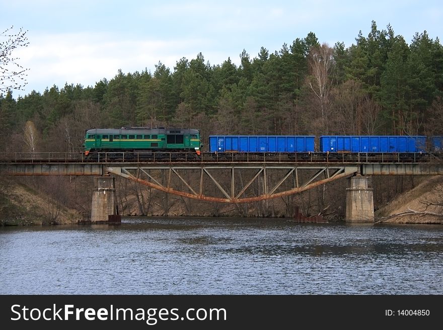 Freight train passing through the steel bridge over the lake. Freight train passing through the steel bridge over the lake