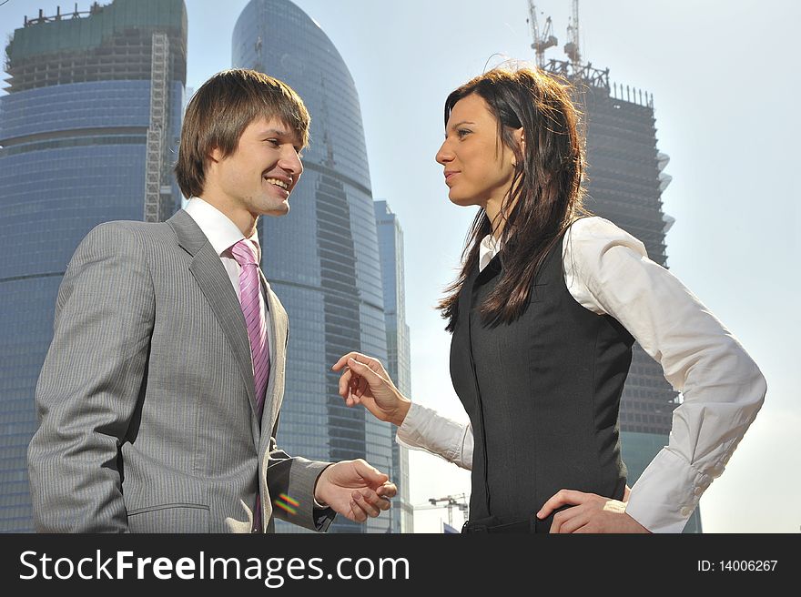 Two businessmen discuss the project against a skyscraper