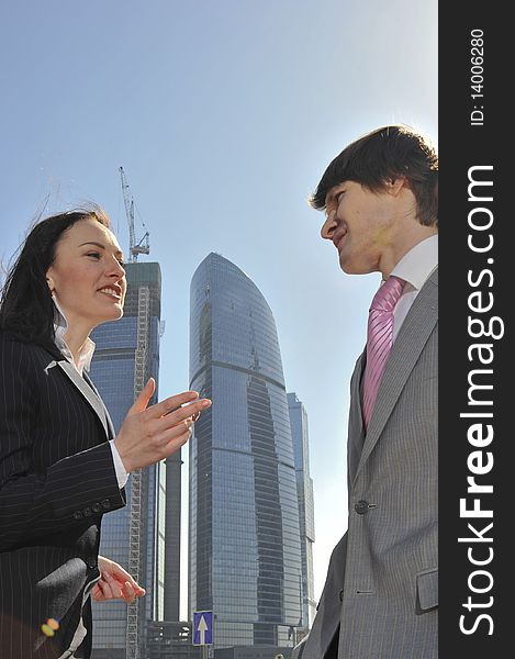 Two businessmen discuss the project against a skyscraper
