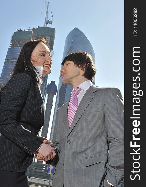 Two businessmen discuss the project against a skyscraper