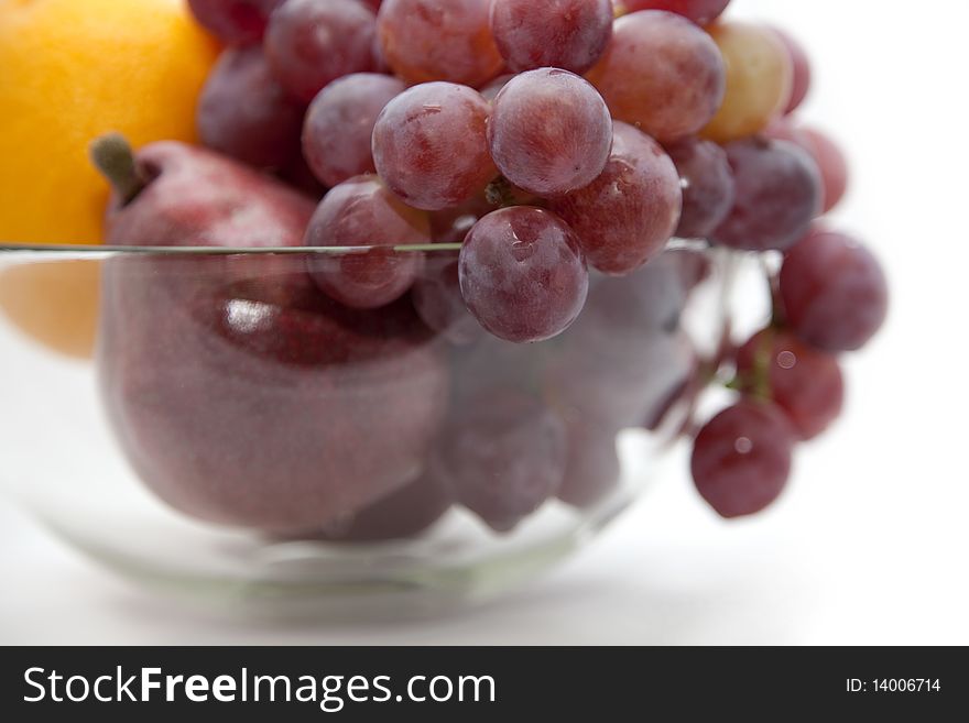Pear, orange and grapes of red colour in a glass vase. Pear, orange and grapes of red colour in a glass vase