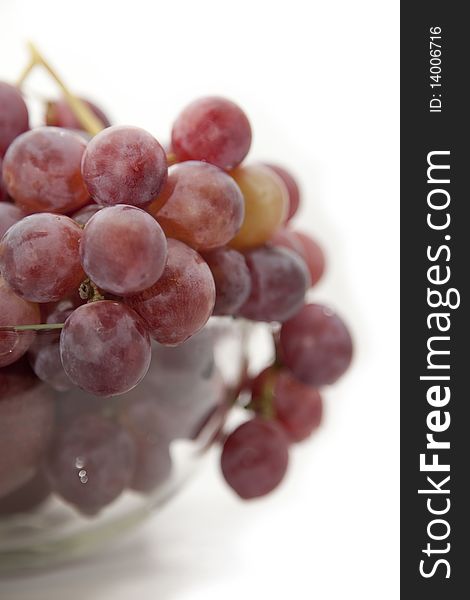 Grapes of red colour in a glass vase on a white background