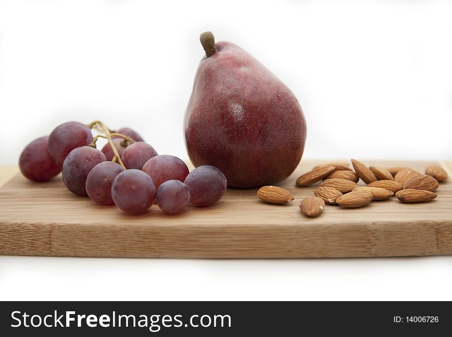 Red grapes, pear and almonds on a kitchen board for are sharp. Red grapes, pear and almonds on a kitchen board for are sharp