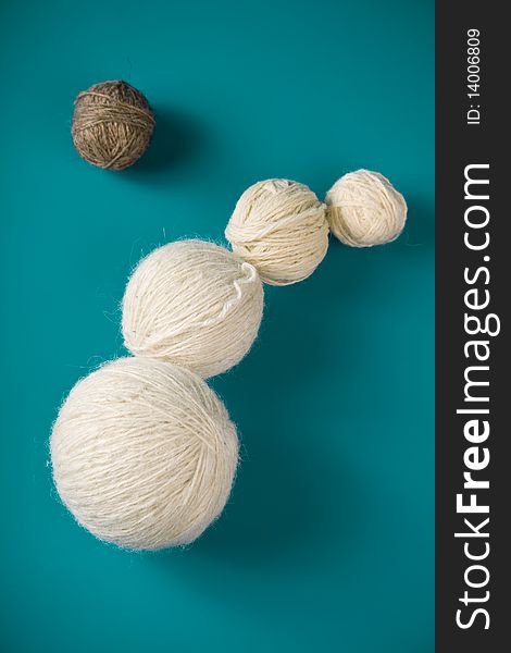 White balls of yarn of various sizes on a blue background