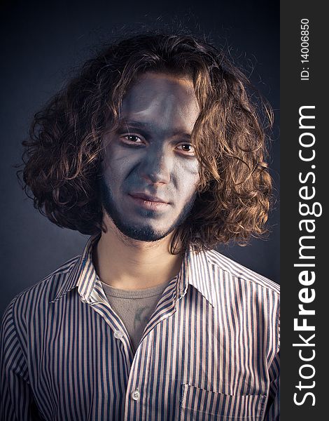 Young man in make-up with long hair on a black background