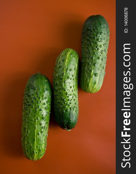 Three green bumps cucumbers on a red background