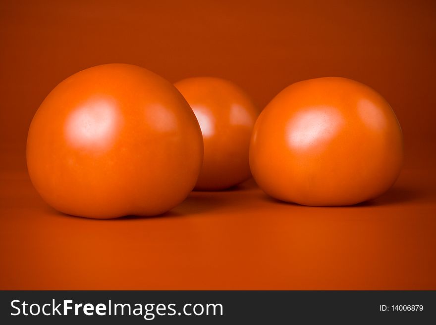 Three ripe red tomatoes  on a red background