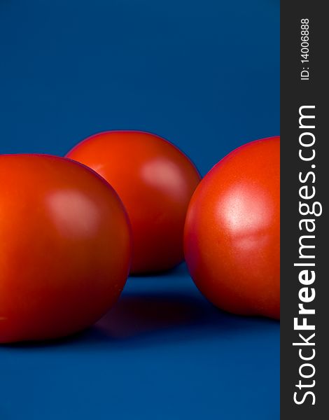 Three ripe red tomatoes on a blue background