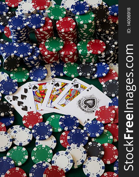 A Royal Flush surrounded by gambling chips on a green felt table. A Royal Flush surrounded by gambling chips on a green felt table.