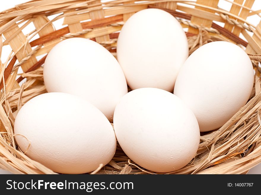 Raw eggs in a basket over white. hen's eggs. Raw eggs in a basket over white. hen's eggs