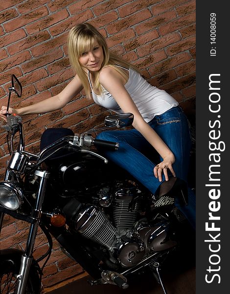 Sexy girl sitting on a motorcycle inside a studio with brick background. Sexy girl sitting on a motorcycle inside a studio with brick background