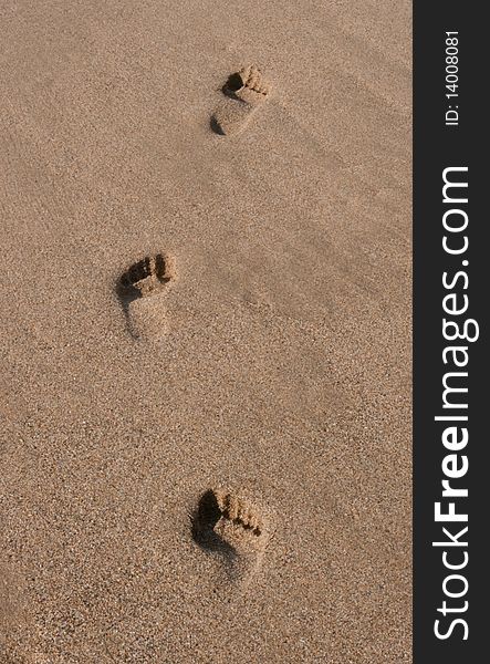 Three footprints on the beach sand