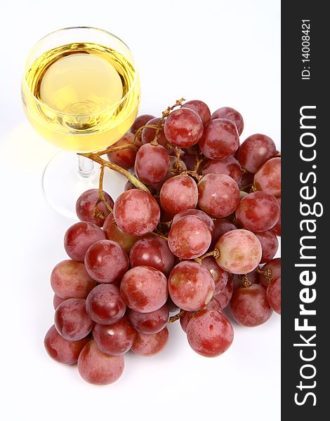 Glass of white wine and red grapes on white background. Glass of white wine and red grapes on white background