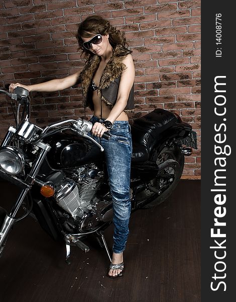 Sexy girl sitting on a motorcycle inside a studio with brick background. Sexy girl sitting on a motorcycle inside a studio with brick background