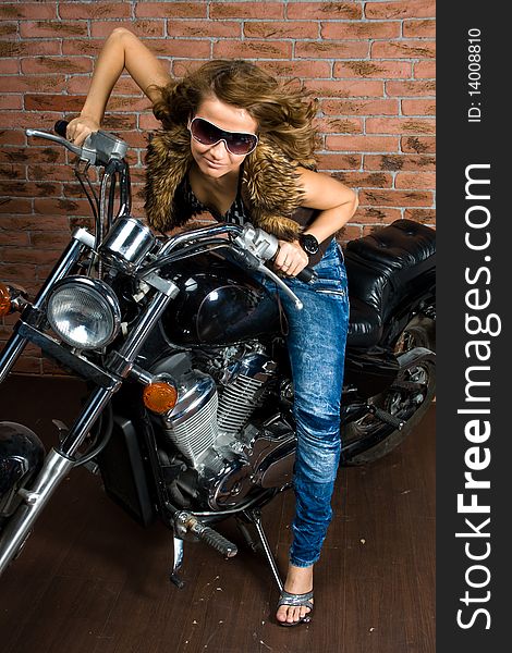 Sexy girl sitting on a motorcycle inside a studio with brick background. Sexy girl sitting on a motorcycle inside a studio with brick background