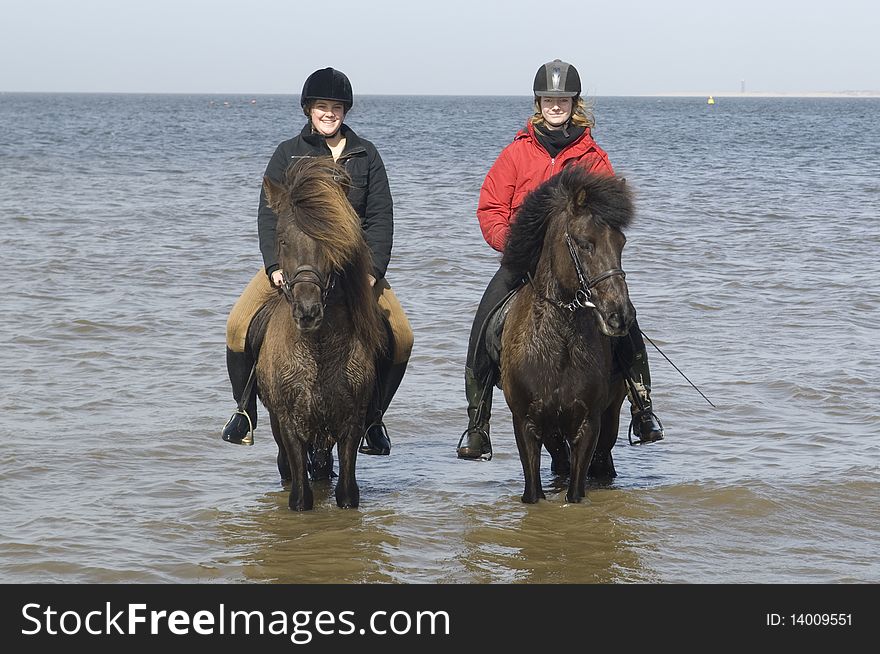 Two amazones on horseback on the beach and in sea