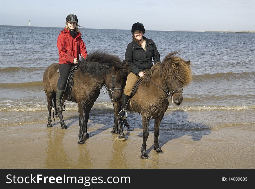 Two amazones on horseback on the beach and in sea